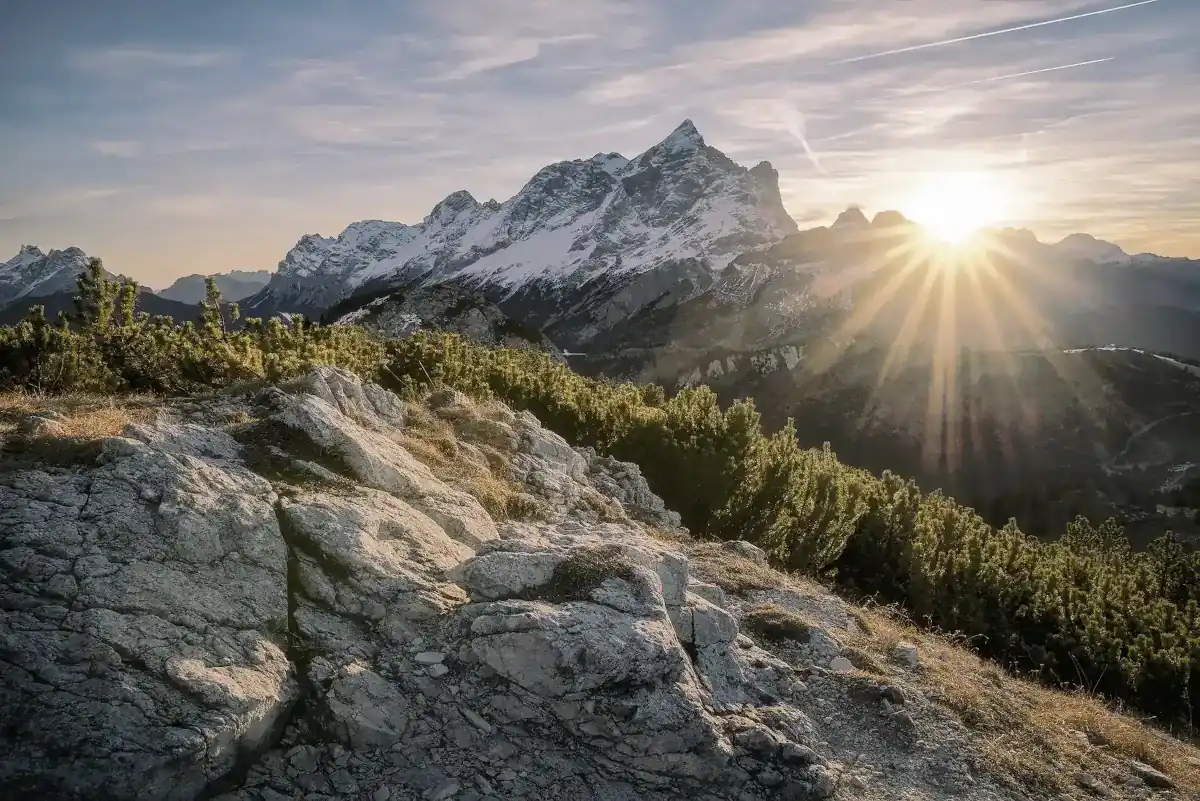 The sun rising over some snowy mountains
